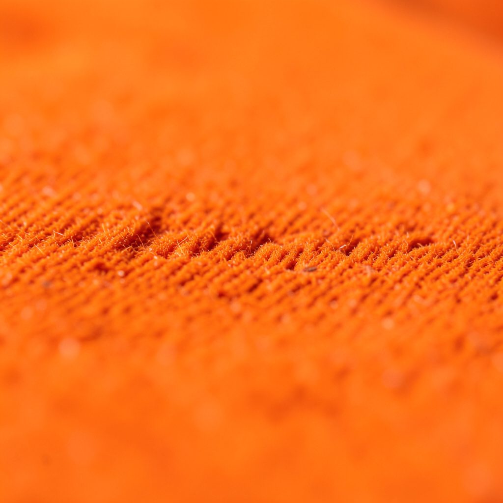 Textura de un bandoneón visto de cerca, con sus botones nacarados brillando sobre un fuelle de color rojo oscuro y negro.