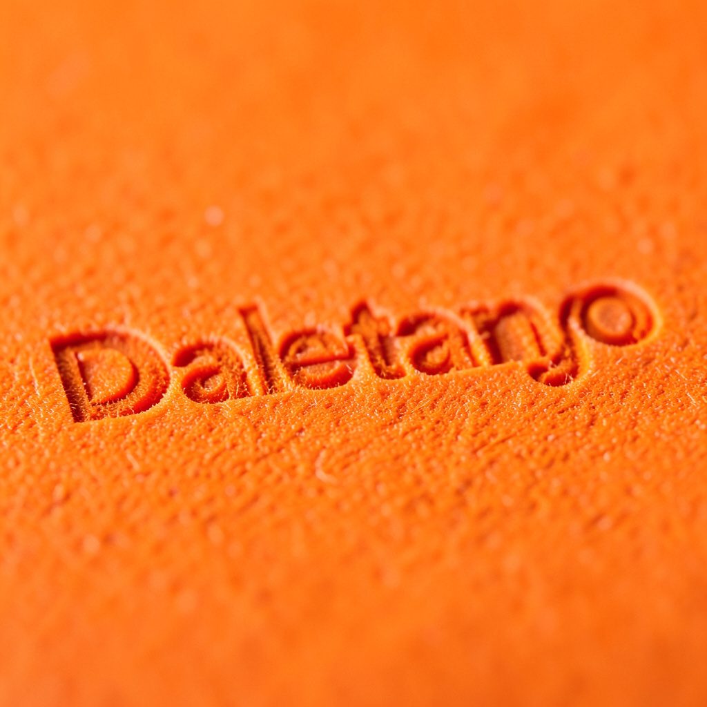 Primer plano extremo de la textura de una tela de seda arrugada en tonos azul marino profundo y naranja cálido, con pliegues suaves que evocan el movimiento del baile.